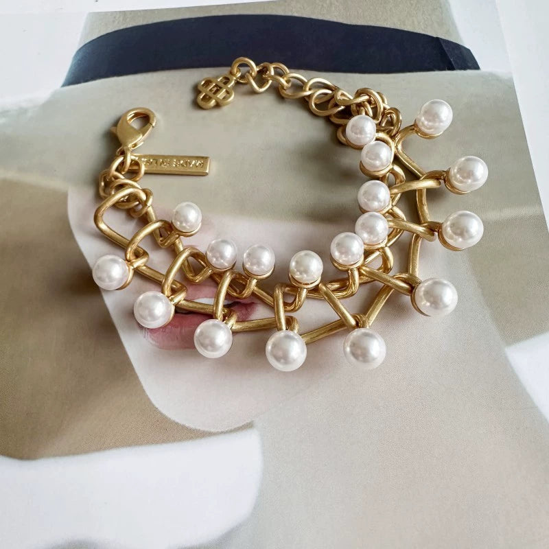 Gold intertwined-link bracelet with white pearl drops and toggle clasp