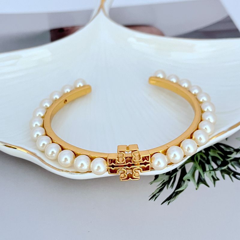 Pearl Logo open bangle: gold-tone cuff with white pearls and red-gold center clasp