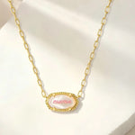 Gold oval pendant necklace with “mama” script and textured edge on curb chain