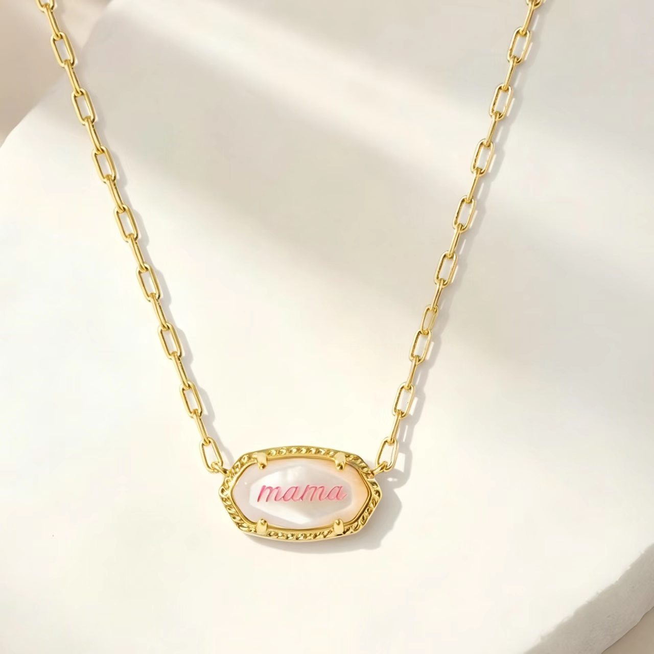 Gold oval pendant necklace with “mama” script and textured edge on curb chain