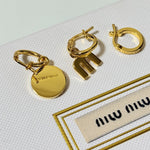 Three-piece enamel hoop earrings with gold round charm and gold-tone metal hoops