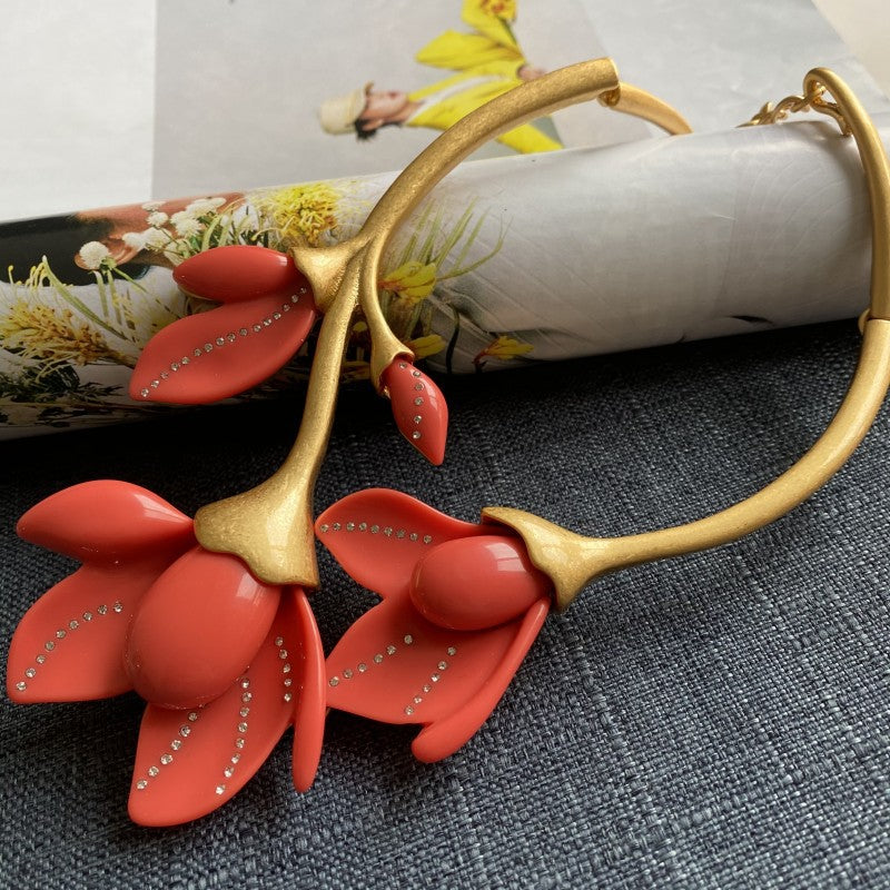 Gold-tone floral hoop necklace with coral red resin petals and rhinestone trim