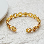 Gold tone clover openwork bangle with faceted links and small cutout four-leaf motifs