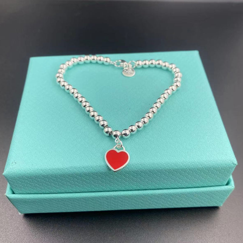 Silver bead heart pendant bracelet with red heart charm on display