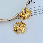 Gold 3D logo metal hoop earring with sculpted floral emblem, close-up