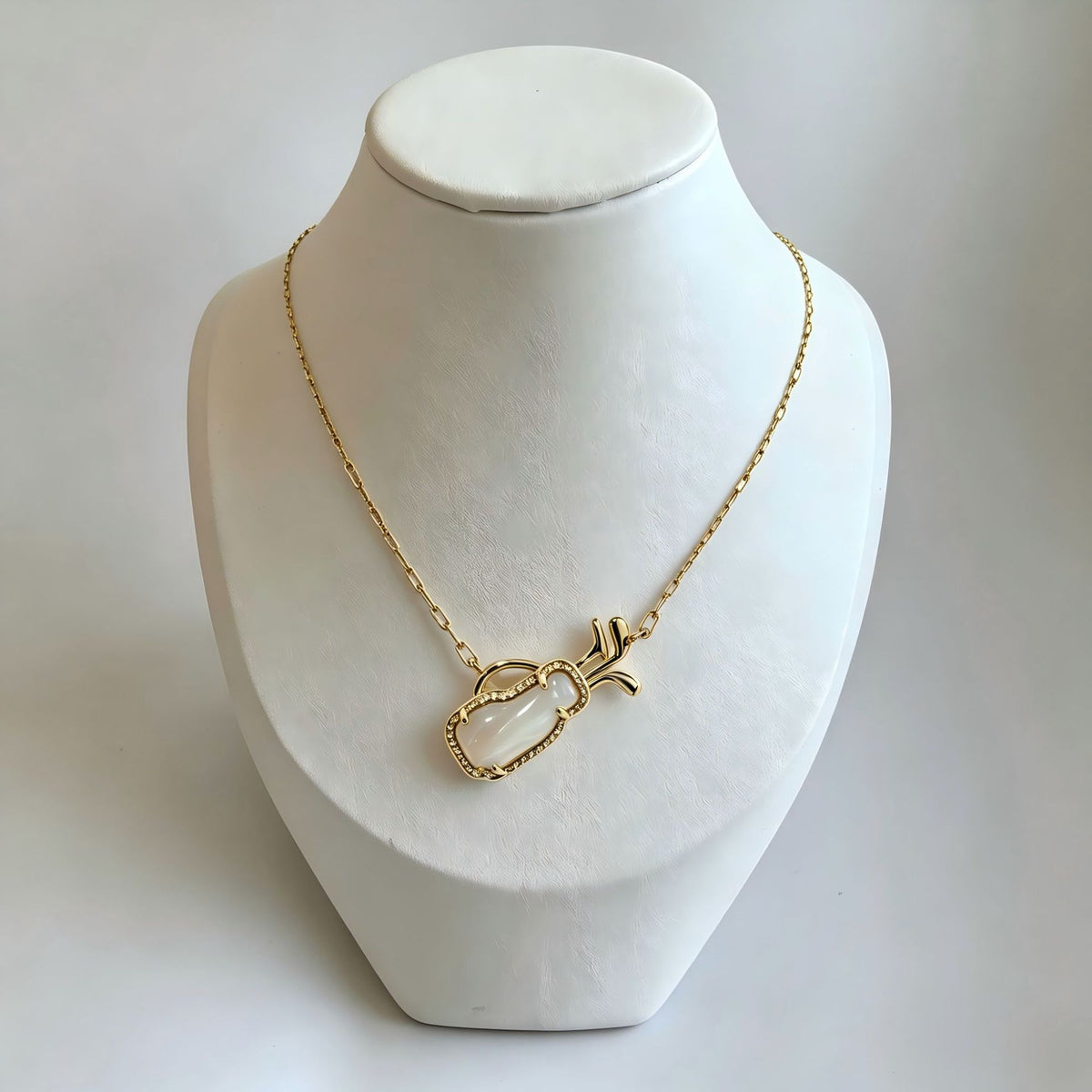 Gold-tone charm necklace on a mannequin with openwork heart pendant and dangling charm