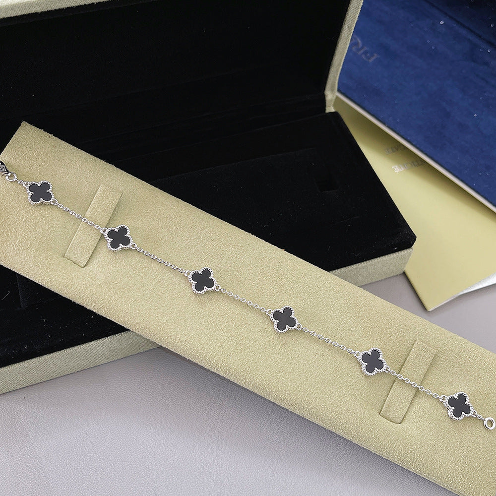Gold tone bracelet with dark four-leaf clover charms on a fine chain