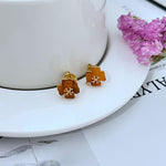 Amber four-leaf clover stud earrings with gold-tone center detail
