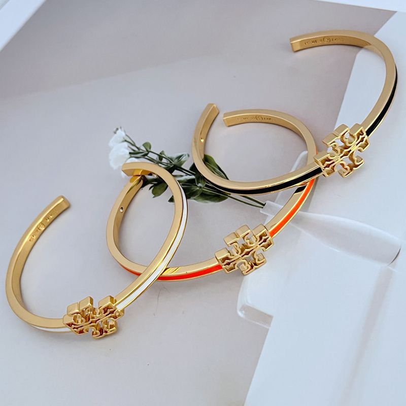 Gold open metal bangle with geometric cutout logo detail on front