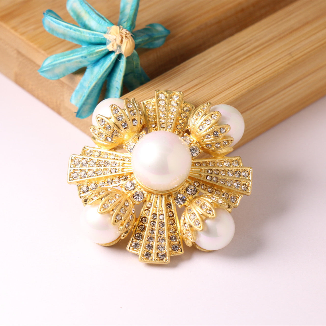 Gold-tone vintage brooch with round pearl center and white pearls around crystal rays