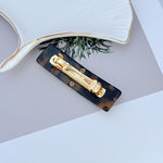 Dark brown acrylic hair clip with gold logo front
