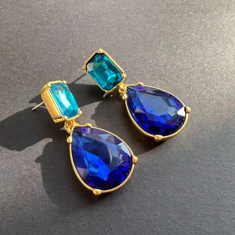 Teardrop-cut diamond stud earrings with bright blue stones in gold-tone settings