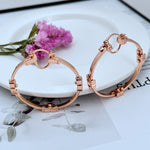 Rose-gold tone high-shine 3D logo round hoop earrings, hinged clasp, metal