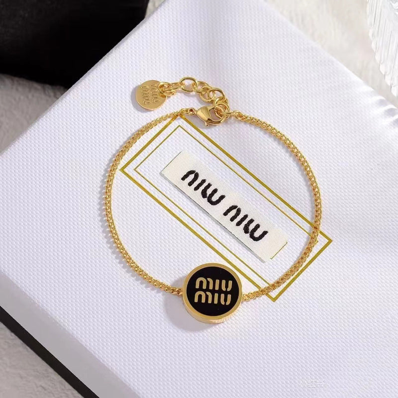 Round black enamel charm bracelet with gold links and adjustable clasp detail.
