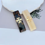 Dark brown acrylic hair clip with gold logo plaque