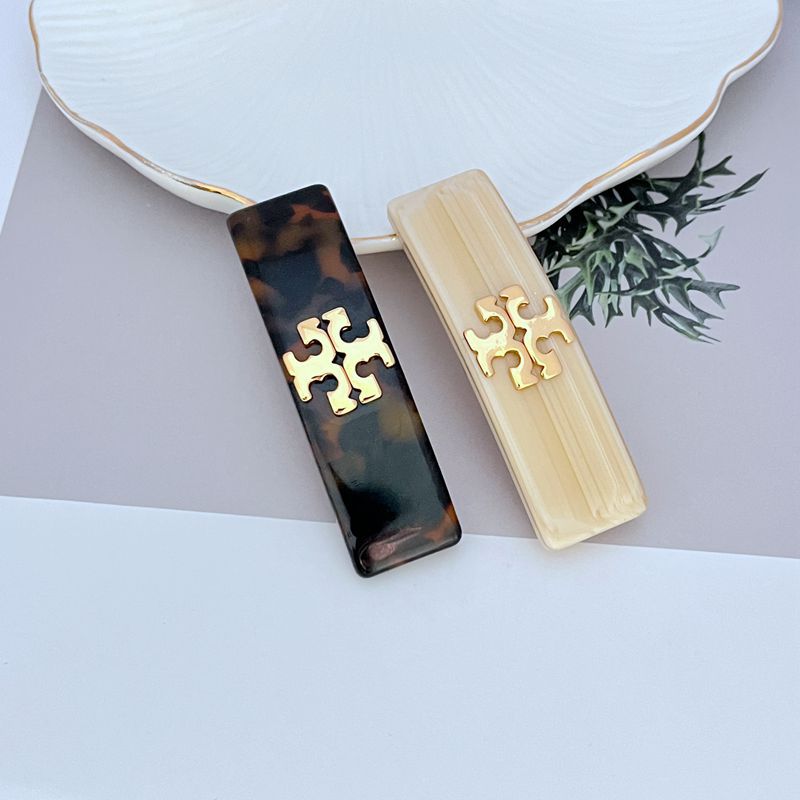 Dark brown acrylic hair clip with gold logo plaque