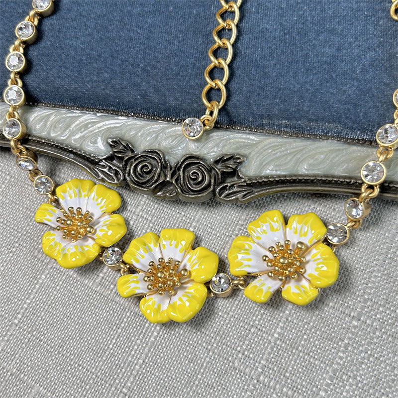 Close-up enamel cherry blossom pendant necklace with yellow flowers on gold filigree centerpiece