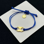 Blue woven adjustable drawstring bracelet with gold clover charm and round coin tag