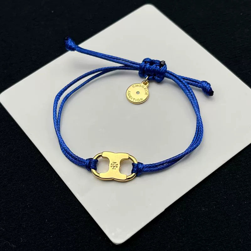 Blue woven adjustable drawstring bracelet with gold clover charm and round coin tag