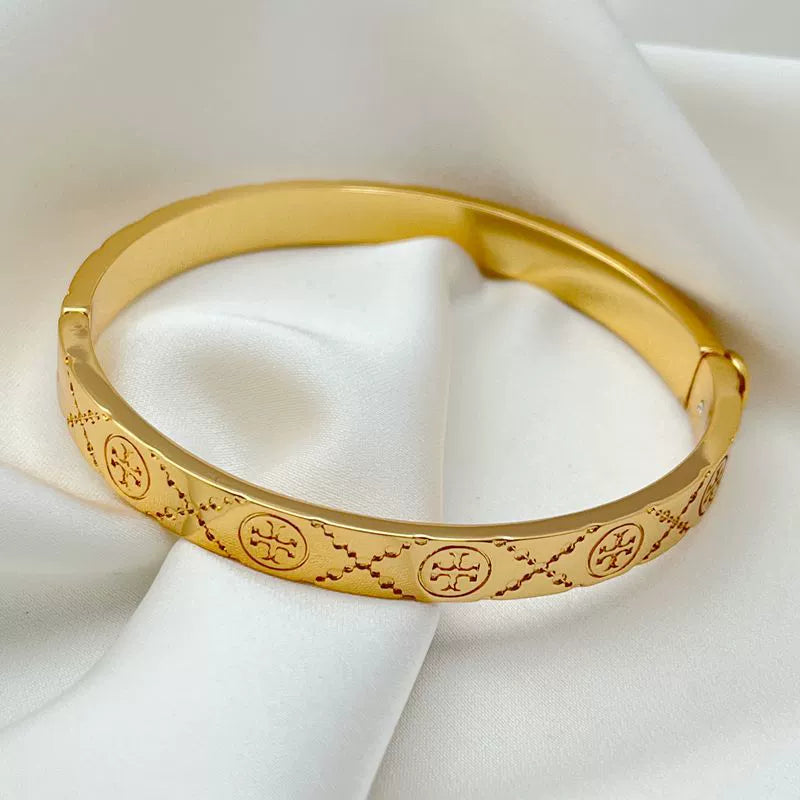 Gold logo-pattern hinged bangle bracelet, side view with etched linework