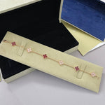 Roségoldfarbenes Armband mit dunkelroten Vierblatt-Anhängern und glitzernden Steinelementen