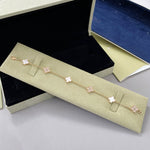 Goldfarbenes Armband mit weißen Kleeblatt-Anhängern und funkelnden Steinbesätzen