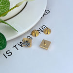 Gold square logo stud earrings with butterfly backs visible, geometric front