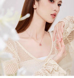 Woman wearing rose-gold flower pendant necklace with pink enamel petals and clear center stones