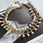 Gold pearl-link bracelet with intertwined chain links and small central emblem