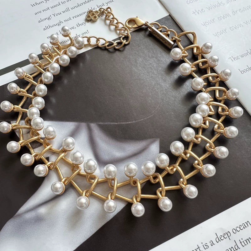 Gold pearl-link bracelet with intertwined chain links and small central emblem