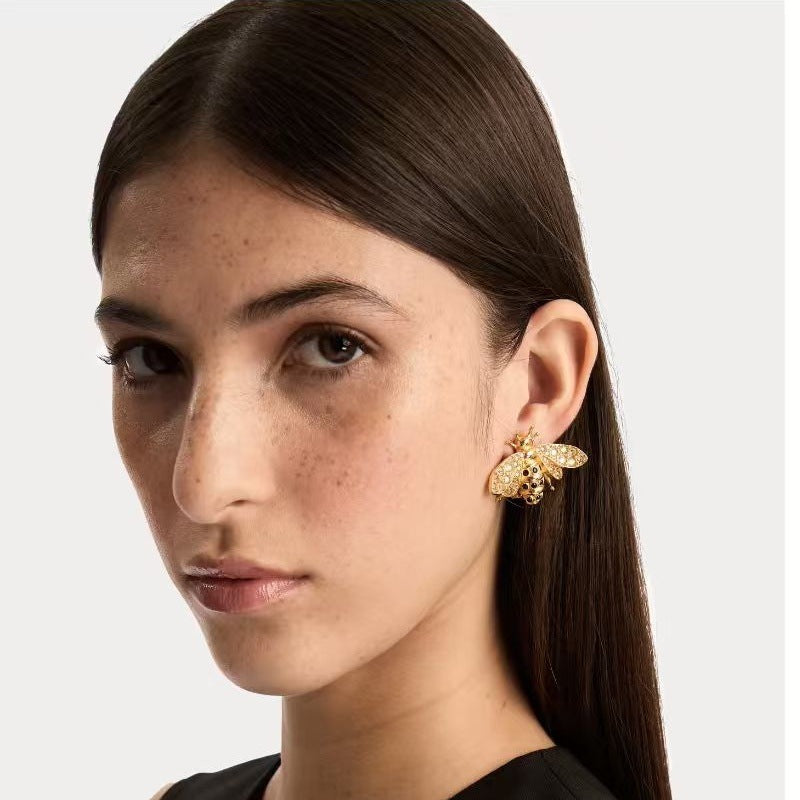 Bee earrings worn on ear, gold-tone insect with clear crystal wings