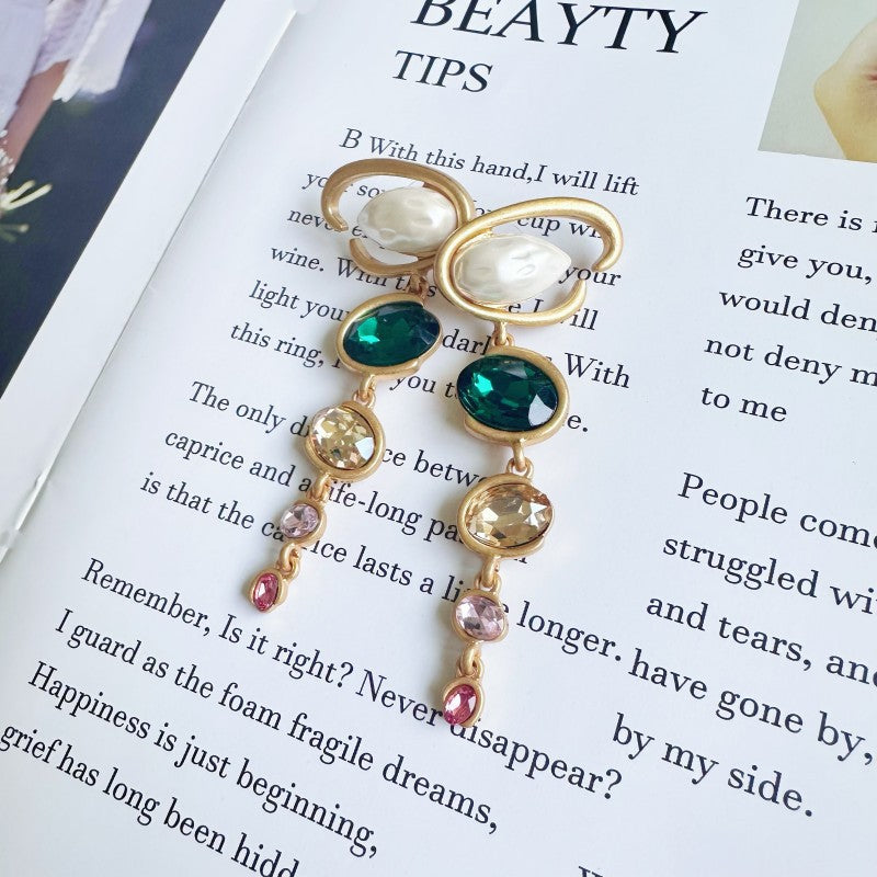 Long crystal drop earrings with gold frames, teal green stones, and small pink accents