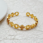 Gold tone clover openwork bangle with linked charms and star-like cutouts