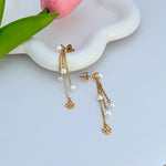 Gold-tone pearl tassel earrings with stud backs, dangling white pearl drops, logo charm