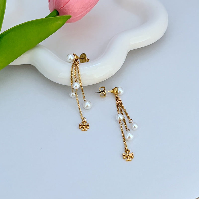 Gold-tone pearl tassel earrings with stud backs, dangling white pearl drops, logo charm
