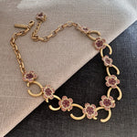 Gold-tone floral O-ring necklace with pink crystal flower clusters and dangling O-links