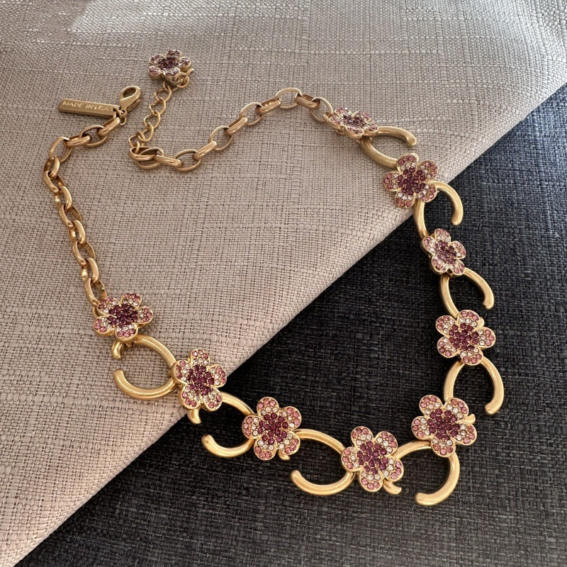 Gold-tone floral O-ring necklace with pink crystal flower clusters and dangling O-links