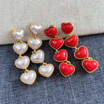 Heart-shaped long drop earrings in white and red pearl hearts with gold-tone links
