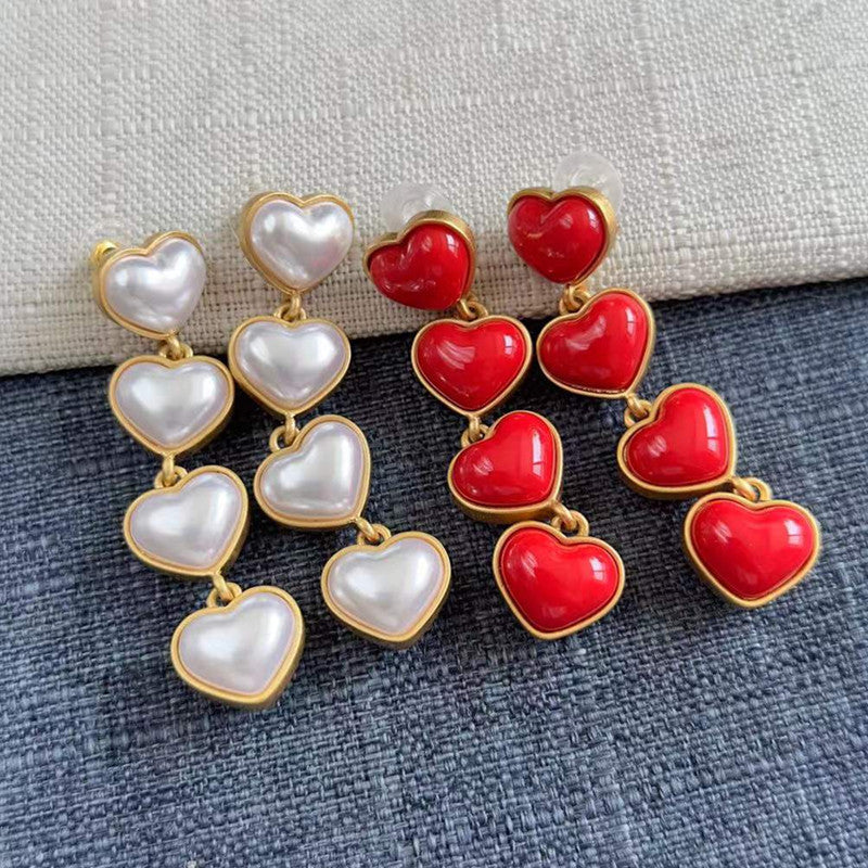 Heart-shaped long drop earrings in white and red pearl hearts with gold-tone links