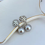 Silver-tone round logo stud earrings with gray pearl drops and pavé border