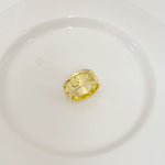 Gold band ring with engraved letter motif and textured side panels