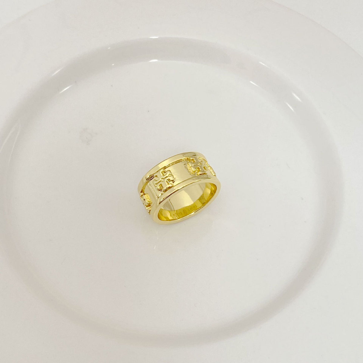 Gold band ring with engraved letter motif and textured side panels
