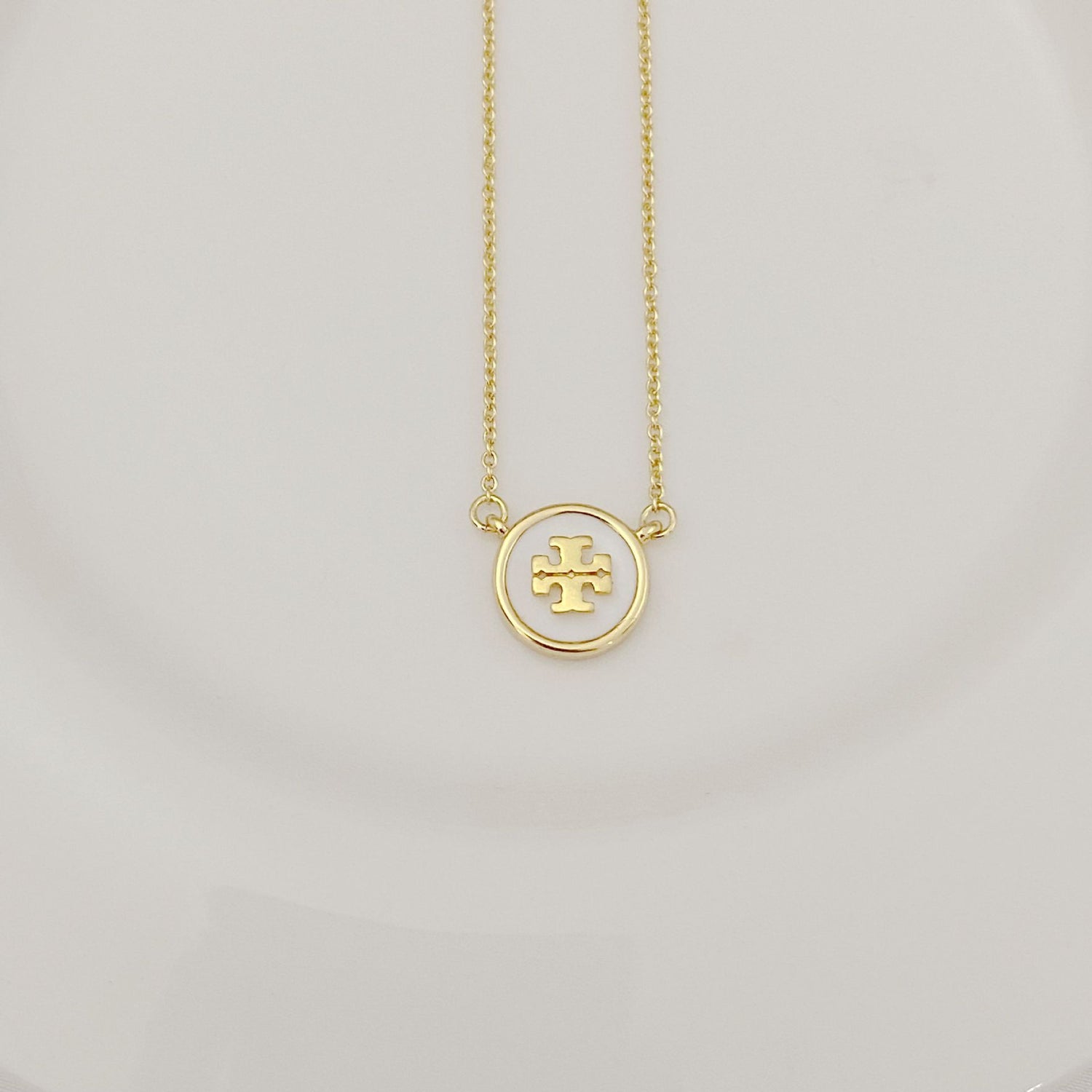 Gold-tone chain necklace with round white enamel logo pendant