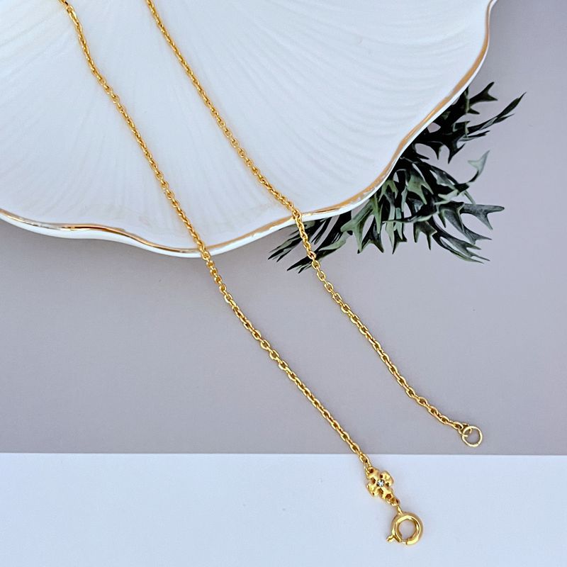 Gold-tone necklace chain with small round clasp and logo charm with sparkle