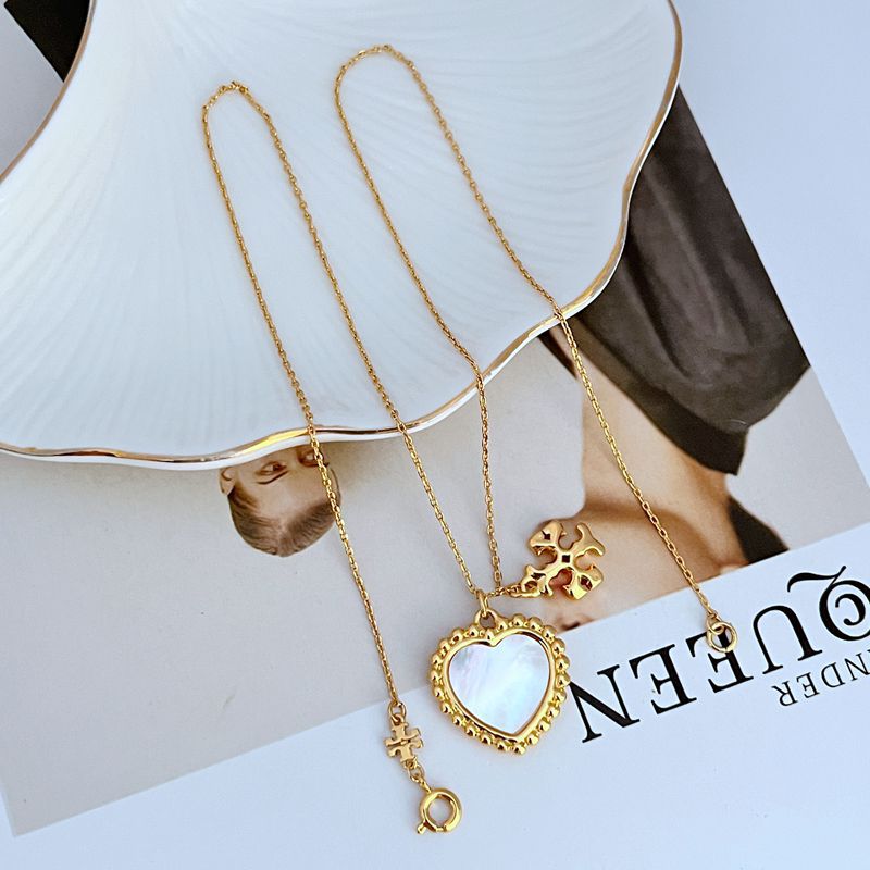 Gold-tone layered necklace with heart shell pendant and small dangling charm