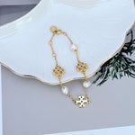 Gold-toned pearl bracelet with puzzle-like charms, adjustable chain and clasp