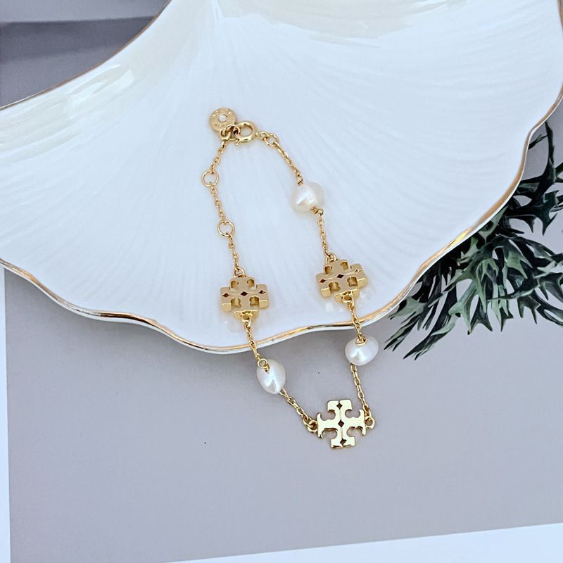 Gold-toned pearl bracelet with puzzle-like charms, adjustable chain and clasp