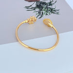 Gold open bangle with heart clasp at one end and mother-of-pearl heart charm