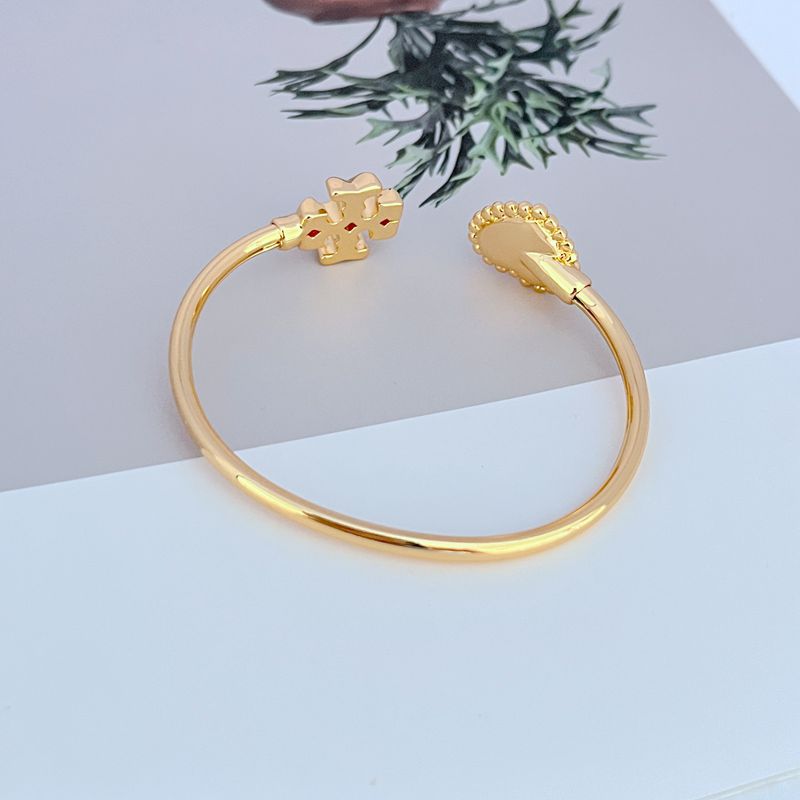 Gold open bangle with heart clasp at one end and mother-of-pearl heart charm