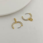 Gold-tone hoop earrings with rhinestone rim and charm, shown from side